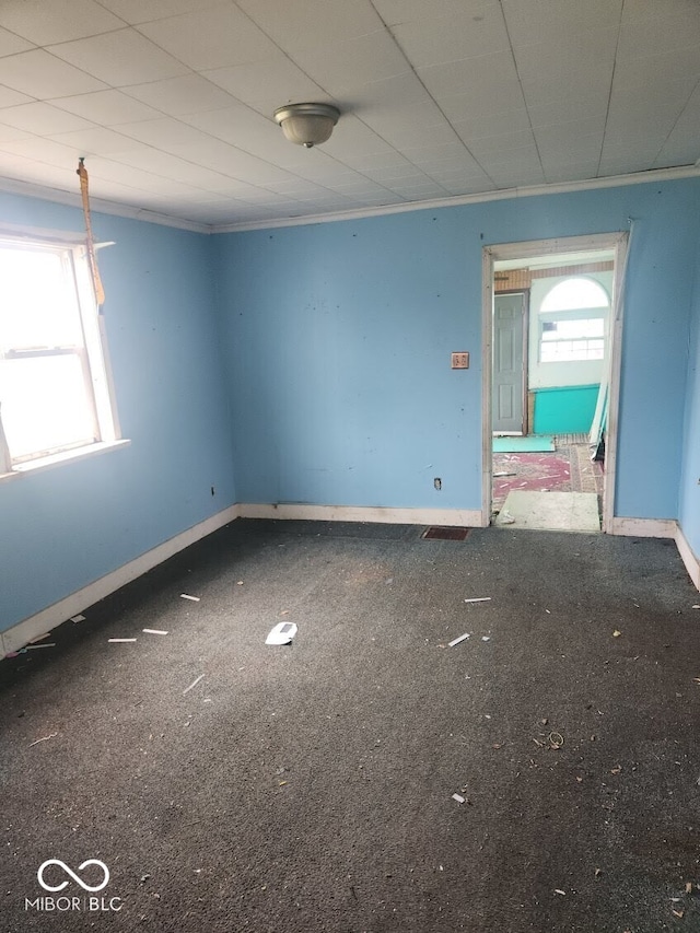 carpeted spare room featuring crown molding and baseboards