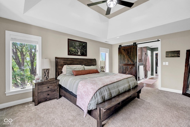 bedroom featuring baseboards, a barn door, light colored carpet, and multiple windows