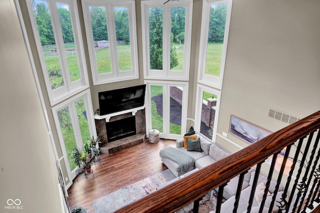 living area with a fireplace, plenty of natural light, wood finished floors, and a high ceiling