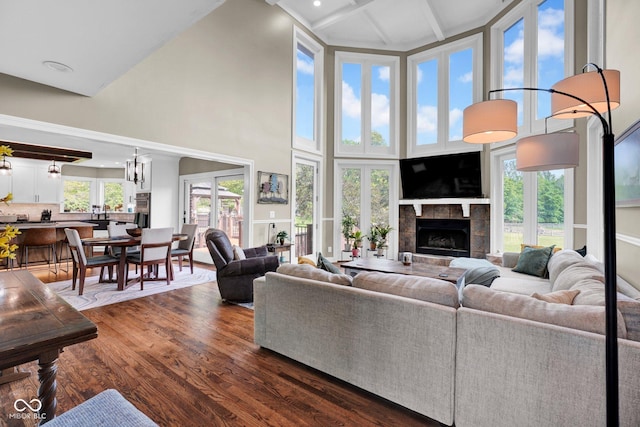 living room with a high ceiling, a tile fireplace, and dark wood-type flooring