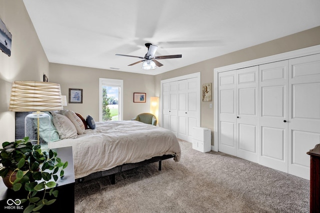 bedroom with carpet, two closets, and a ceiling fan
