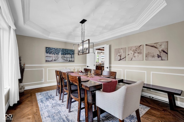 dining room featuring a tray ceiling, a decorative wall, a chandelier, crown molding, and a wainscoted wall