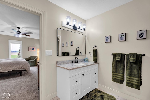 ensuite bathroom with vanity, ceiling fan, baseboards, and tile patterned flooring
