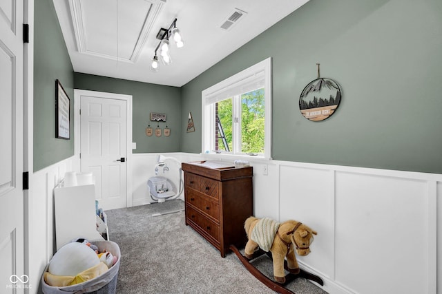 bedroom with attic access, a wainscoted wall, carpet floors, and a decorative wall