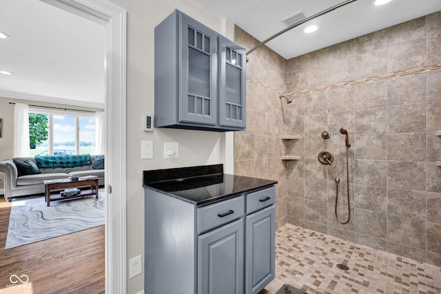 kitchen with gray cabinetry, glass insert cabinets, recessed lighting, open floor plan, and dark stone countertops