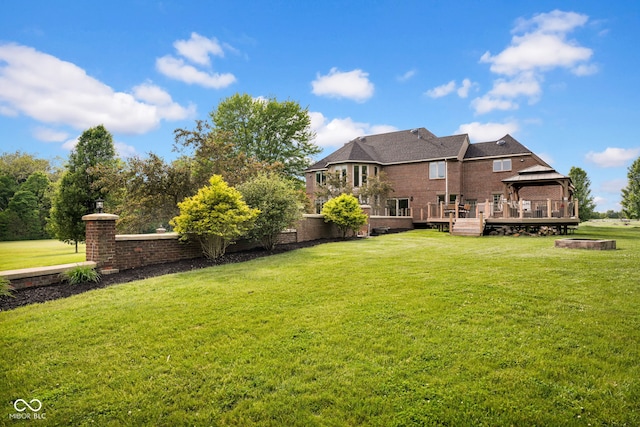 back of house with a gazebo, a deck, a yard, and brick siding