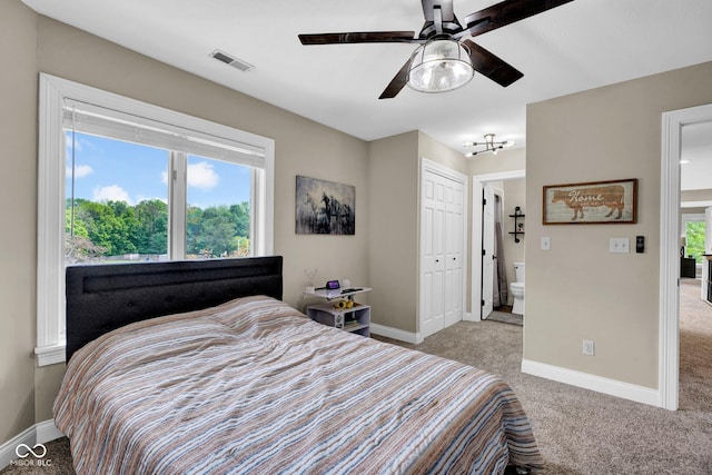 carpeted bedroom featuring baseboards, a closet, ensuite bath, and ceiling fan