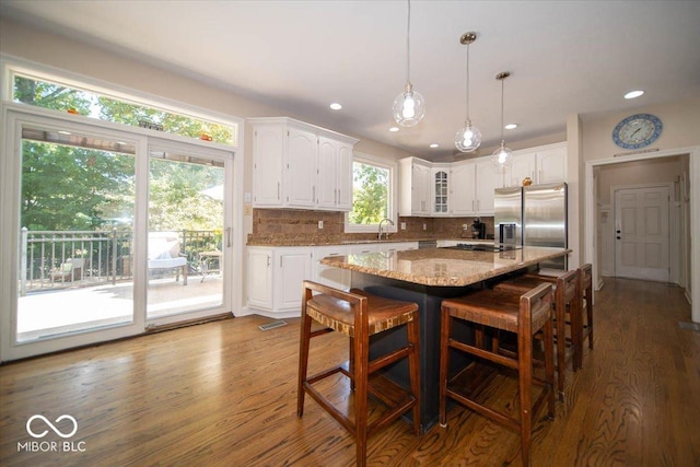 11536 Woods Bay Ln, Indianapolis, IN 46236 - kitchen featuring white cabinetry, stainless steel refrigerator with ice dispenser, wood finished floors, a breakfast bar, and light stone counters