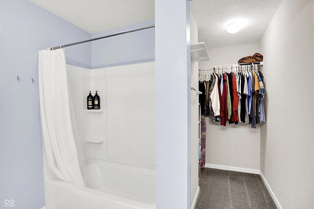 bathroom with baseboards, a walk in closet, and a textured ceiling