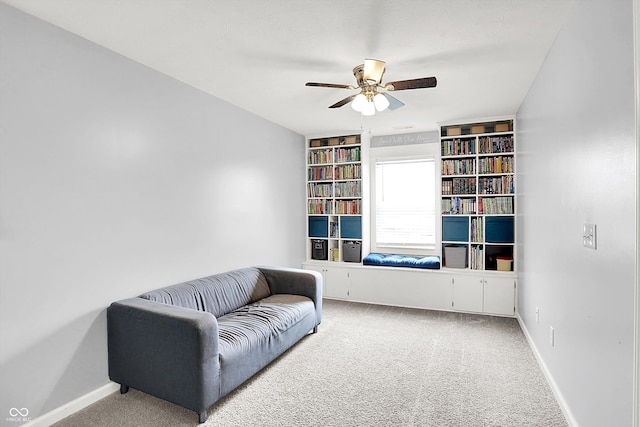 sitting room with carpet, ceiling fan, baseboards, and built in shelves