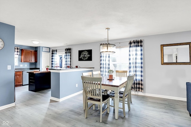 dining room with baseboards, light wood-type flooring, and a textured ceiling