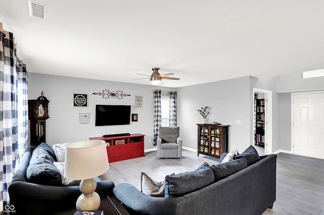 living area featuring wood finished floors, ceiling fan, and baseboards