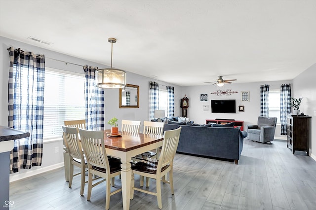 dining area featuring light wood-style floors, baseboards, and ceiling fan