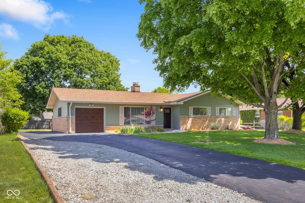 8120 E 11th St, Indianapolis, IN 46219 - ranch-style home with brick siding, an attached garage, a chimney, and driveway