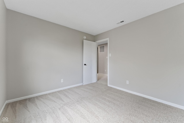 spare room featuring light carpet and baseboards