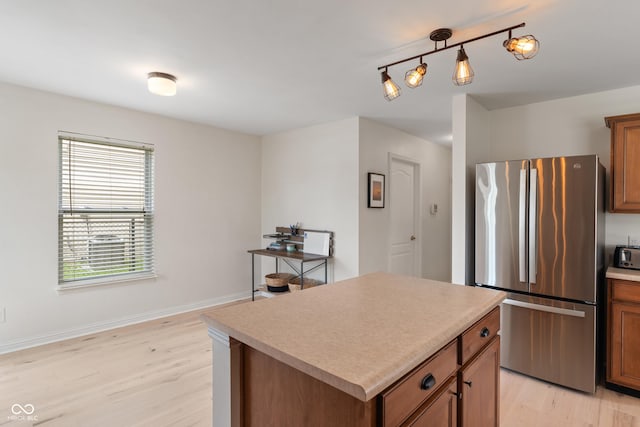 8238 Crackling Ln, Indianapolis, IN 46259 - kitchen with freestanding refrigerator, light wood-style flooring, brown cabinets, a kitchen island, and light countertops