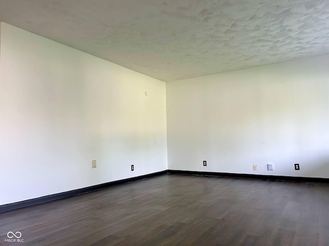 unfurnished room featuring dark wood finished floors, baseboards, and a textured ceiling