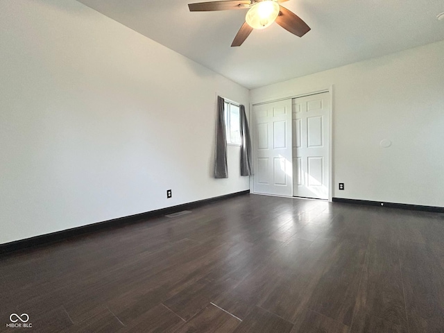 unfurnished bedroom with dark wood-style flooring, baseboards, a closet, and a ceiling fan
