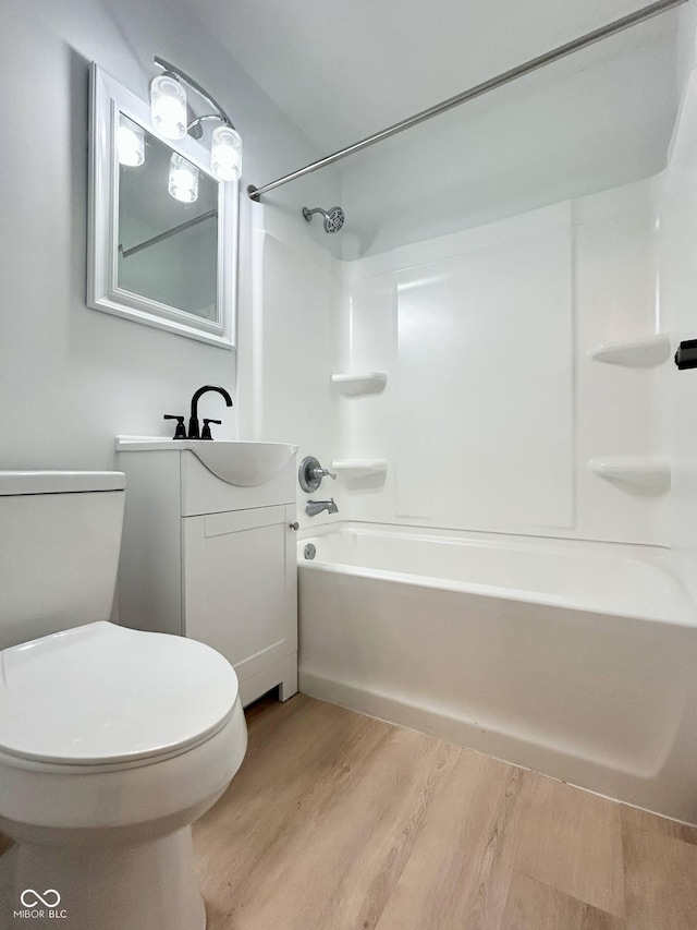 bathroom featuring wood finished floors, toilet, washtub / shower combination, and vanity