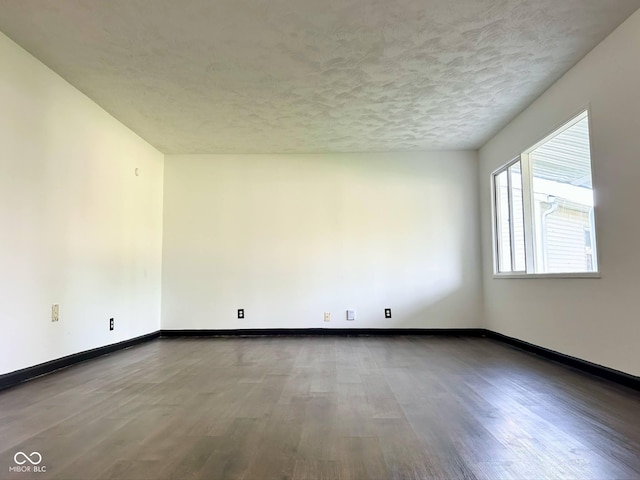 spare room featuring wood finished floors, baseboards, and a textured ceiling