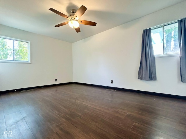 empty room with dark wood finished floors, ceiling fan, and baseboards