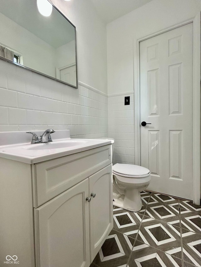half bathroom with tile walls, vanity, and toilet