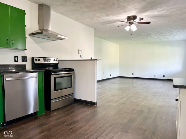 kitchen with stainless steel appliances, wall chimney exhaust hood, dark wood-style flooring, dark countertops, and a textured ceiling
