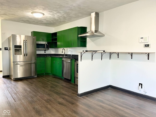 kitchen featuring appliances with stainless steel finishes, wall chimney exhaust hood, green cabinets, dark wood-style flooring, and a textured ceiling