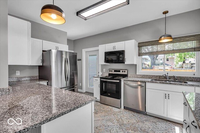 405 N Drexel Ave, Indianapolis, IN 46201 - kitchen featuring stainless steel appliances, a sink, white cabinetry, dark stone countertops, and hanging light fixtures