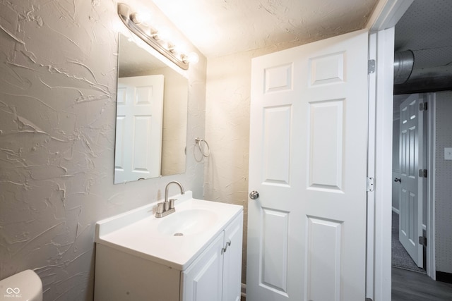 2740 Pawnee Dr, Indianapolis, IN 46229 - bathroom with a textured wall, vanity, and wood finished floors