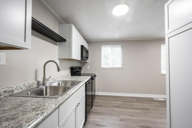 2740 Pawnee Dr, Indianapolis, IN 46229 - kitchen featuring black appliances, a sink, white cabinets, baseboards, and light wood-type flooring