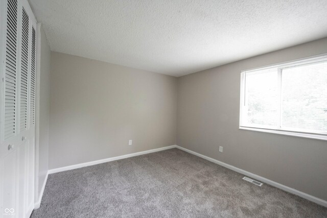 2740 Pawnee Dr, Indianapolis, IN 46229 - unfurnished bedroom featuring carpet, a closet, baseboards, and a textured ceiling