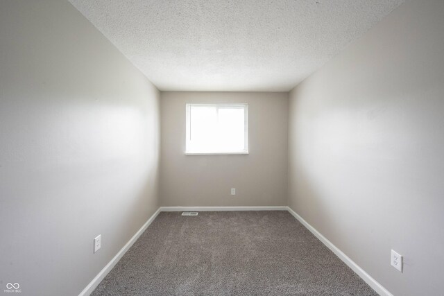 2740 Pawnee Dr, Indianapolis, IN 46229 - empty room featuring a textured ceiling, carpet, and baseboards