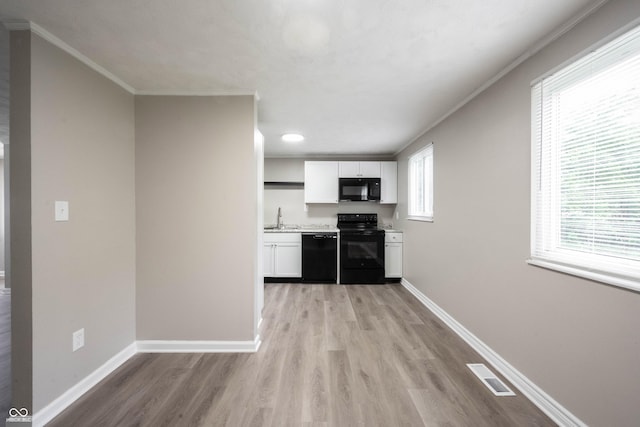 2740 Pawnee Dr, Indianapolis, IN 46229 - kitchen with black appliances, a sink, ornamental molding, white cabinetry, and light wood-type flooring