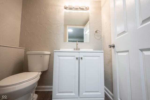 2740 Pawnee Dr, Indianapolis, IN 46229 - half bathroom featuring a textured wall, vanity, toilet, wood finished floors, and baseboards