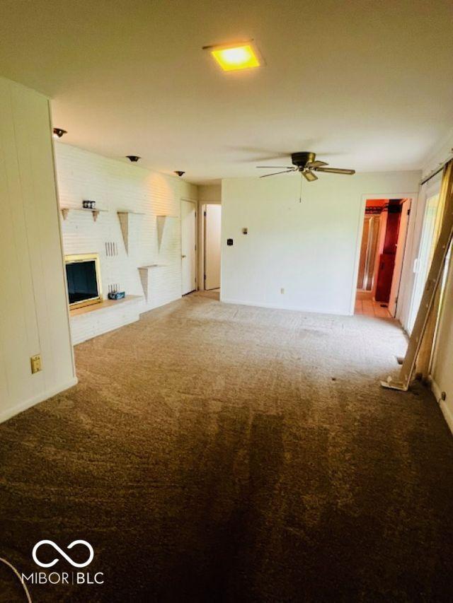5141 Derome Dr, Fort Wayne, IN 46835 - unfurnished living room with carpet flooring, ceiling fan, and a large fireplace