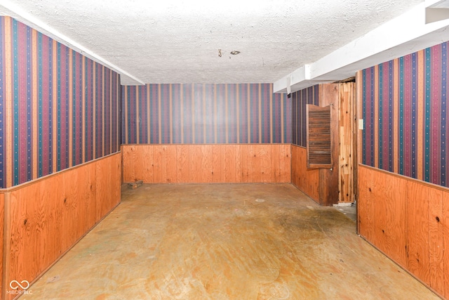 3325 Broadview Ct, Indianapolis, IN 46227 - spare room with wainscoting, a textured ceiling, wood walls, wallpapered walls, and concrete floors