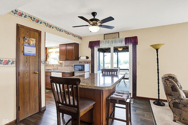 kitchen with stainless steel microwave, a sink, dark wood-style flooring, and a ceiling fan