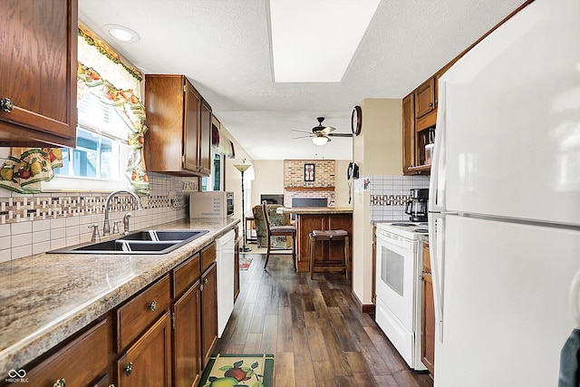 kitchen featuring white appliances, a sink, a ceiling fan, tasteful backsplash, and dark wood-style flooring