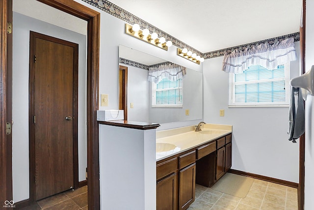 bathroom with double vanity, baseboards, and tile patterned floors