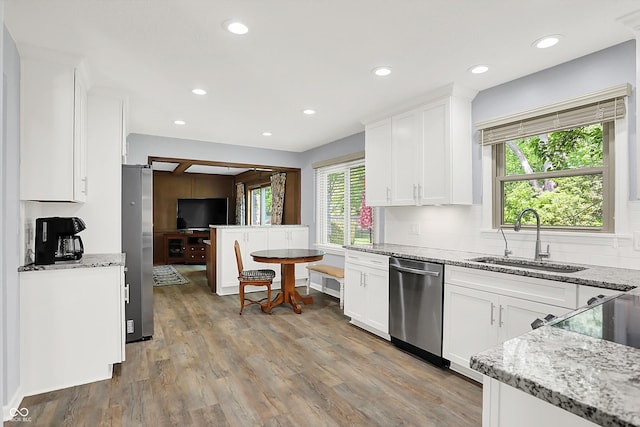 781 Dayton Dr, Carmel, IN 46033 - kitchen with stainless steel appliances, a sink, white cabinets, light wood-style flooring, and decorative backsplash