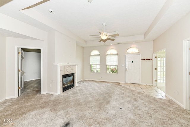 7645 Briarstone Ln, Indianapolis, IN 46227 - unfurnished living room featuring a tray ceiling, light carpet, a ceiling fan, a tiled fireplace, and light tile patterned floors