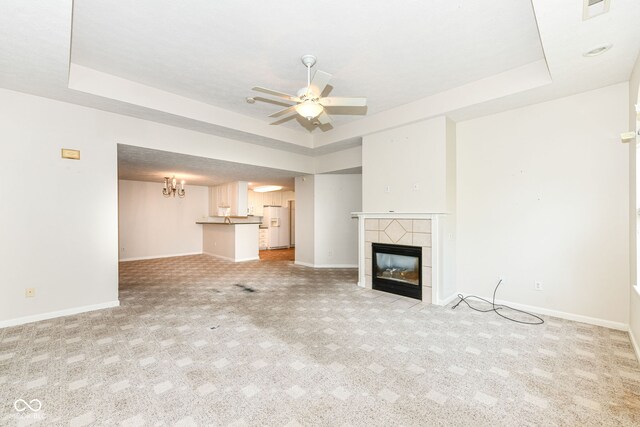 7645 Briarstone Ln, Indianapolis, IN 46227 - unfurnished living room with a raised ceiling, a ceiling fan, a tiled fireplace, and light carpet