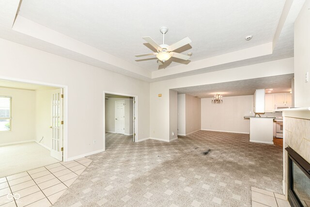 7645 Briarstone Ln, Indianapolis, IN 46227 - unfurnished living room with light carpet, a raised ceiling, ceiling fan, a tile fireplace, and a chandelier