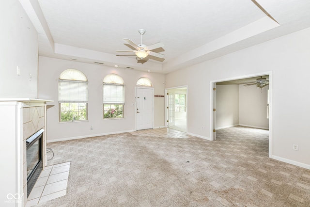 7645 Briarstone Ln, Indianapolis, IN 46227 - unfurnished living room with a tray ceiling, a ceiling fan, a tile fireplace, and light colored carpet