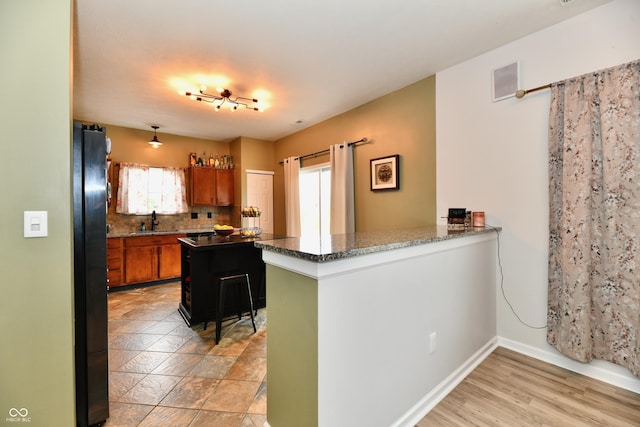 7604 Cloudy Ct, Camby, IN 46113 - kitchen featuring freestanding refrigerator, brown cabinets, a sink, tasteful backsplash, and dark stone countertops