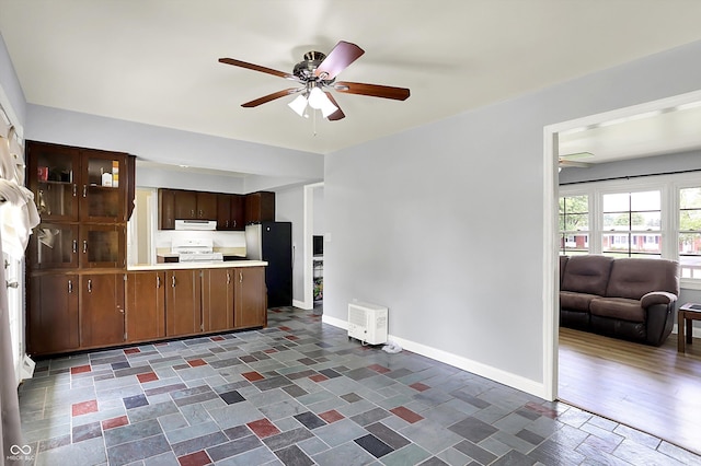 kitchen featuring ceiling fan, freestanding refrigerator, range hood, open floor plan, and white gas stove