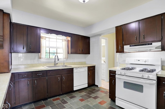 kitchen with white appliances, under cabinet range hood, a sink, light countertops, and decorative backsplash