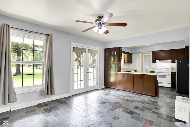 kitchen featuring gas range gas stove, range hood, freestanding refrigerator, light countertops, and a ceiling fan