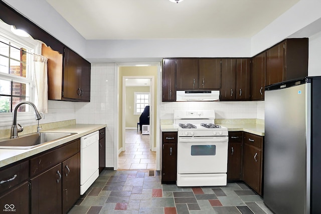 kitchen featuring white appliances, ventilation hood, a sink, and light countertops